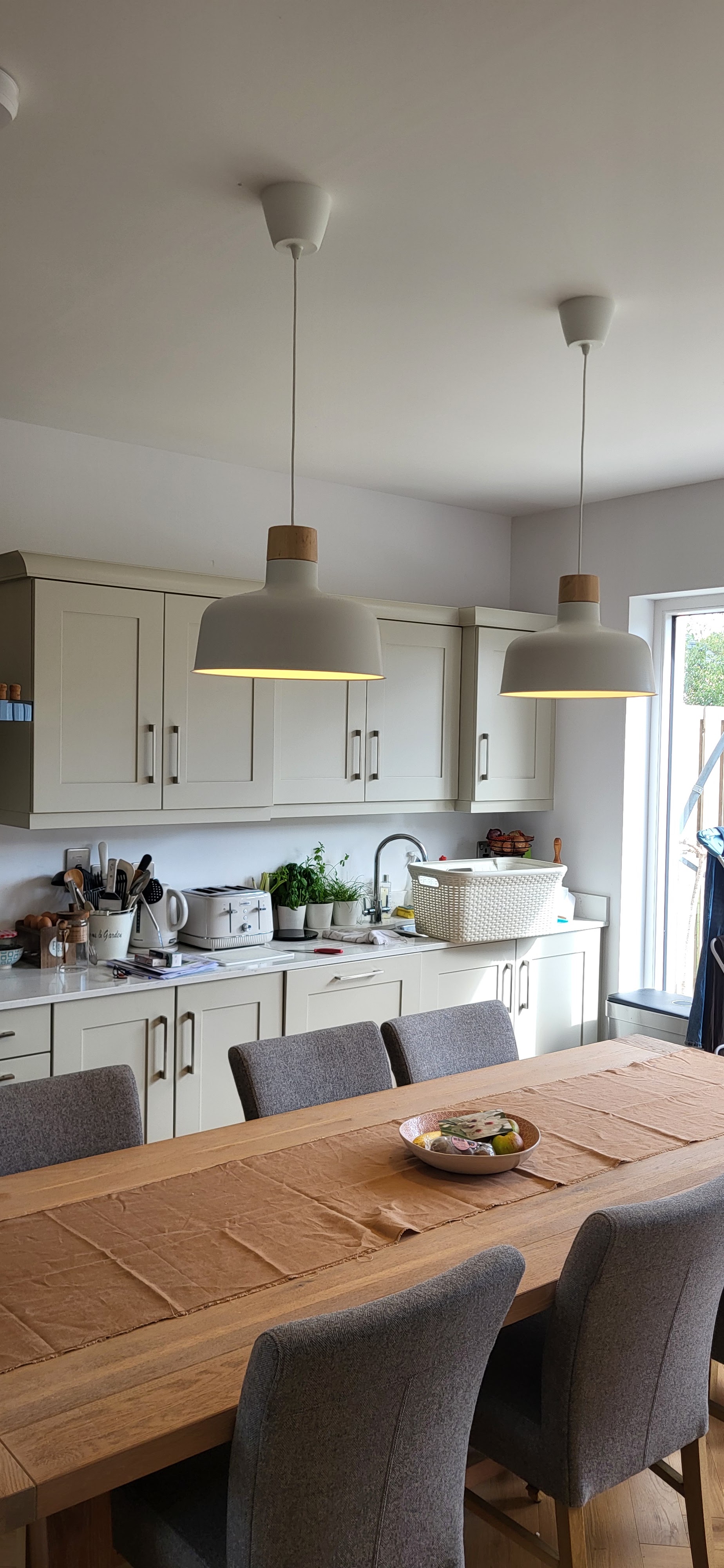 Two pendant lights over a dining table in a kitchen